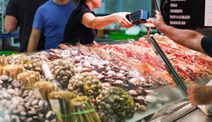 Customer paying at seafood market - Soft focus on hand holding card terminal