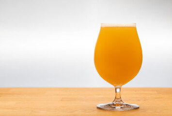 Full tulip glass of NEIPA ale beer on a table - obrazy, fototapety, plakaty