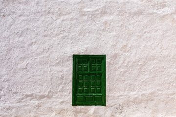 Rustic green wooden door in weathered white wall