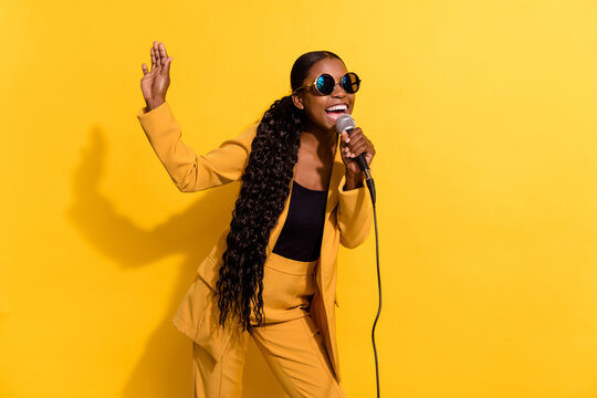 Portrait of attractive cheerful girl singing hit pop having fun good mood isolated on bright yellow color background
