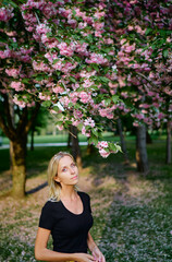 Blonde young woman at blossom garden.