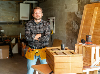 Portrait of young adult carpenter man standing in his carpentry workshop local small business.