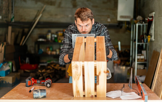 Joiner craftsperson man measuring woodwork product using an angle ruler.