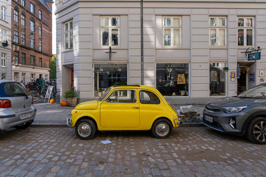 Copenhagen, Denmark - October 18, 2022: A yellow vintage Fiat 500 parked in a street