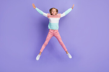 Full length photo of excited shiny little lady dressed sweatshirt jumping high like star isolated purple color background