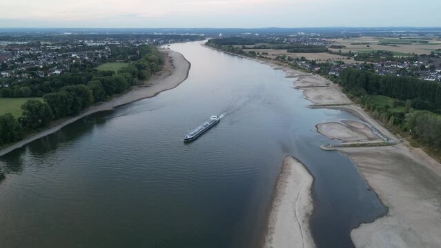 Aerial drone flight around a cargo inland vessel ship transporting oil gas or other liquids on the river Rhein in Cologne, Germany - in extreme dry summer 2022 with low water level near sand bank
