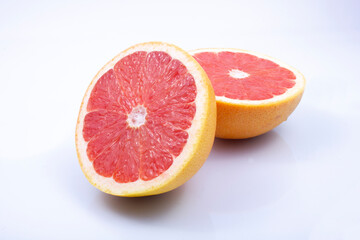 Fototapeta na wymiar juicy, fresh red grapefruit on a grey, two halves of the fruit