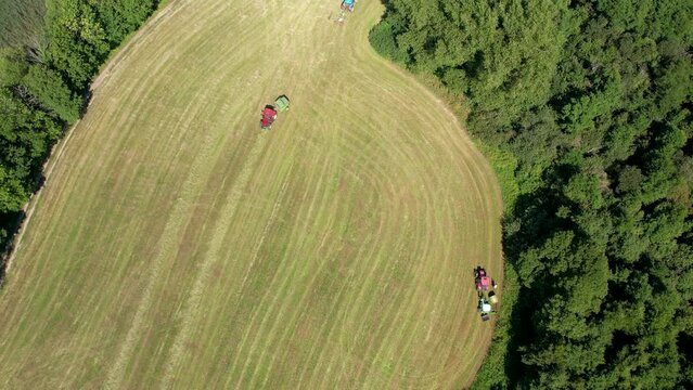 Bird's Eye View Of Agricultural Equipment Working On Green Field In Chmielno, Poland - drone shot