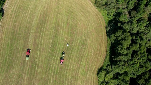 Aerial Birds Eye View Of Pair Of Tractors On Green Field In Chmielno. Slow Descending Shot