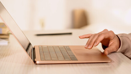Cropped view of woman using laptop with blank screen on table.