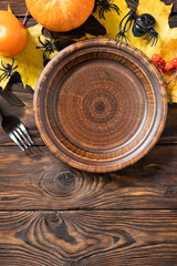 Top view of blank halloween plate with pumpkins on a rustic table. Halloween table setting with cutlery. Festive concept. Copy space.