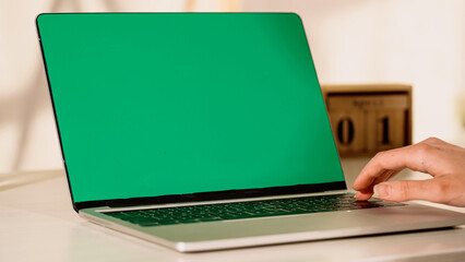 Cropped view of freelancer using laptop with chroma key at home.