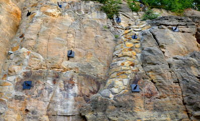 reinforcing the slope with a steel net anchored deep into the rock. falling loose rock stones do...