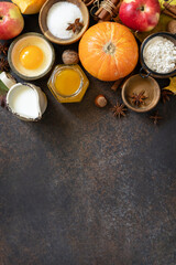 Autumn baking food background with pumpkins, apples, honey, nuts and seasonal spices on a stone table. Pumpkin or apple pie for Thanksgiving and autumn holidays. View from above. Copy space.