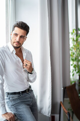 Handsome young unshaven business man in white shirt posing in the office