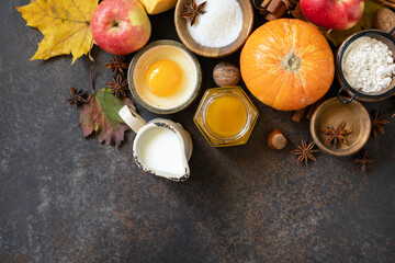 Fototapeta na wymiar Autumn baking food background with pumpkins, apples, honey, nuts and seasonal spices on a stone table. Pumpkin or apple pie for Thanksgiving and autumn holidays. View from above. Copy space.