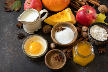Autumn baking food background with pumpkins, apples, honey, nuts and seasonal spices on a stone table. Pumpkin or apple pie for Thanksgiving and autumn holidays. Copy space.