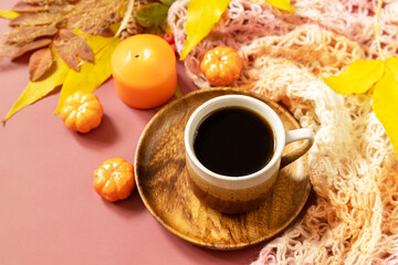 Autumnal breakfast. Composition fall leaves, hot cup of coffee and warm scarf. Cozy autumn season concept. Copy space.