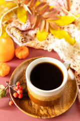 Composition fall leaves, hot cup of coffee and warm scarf. Autumnal breakfast. Cozy autumn season concept.