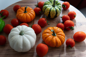 colorful pumpkins with tomatoes on a wooden table with a blurred background. autumn harvest atmosphere.
