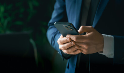 Businessman in suit with mobile phone in hands. Man typing message, using social net. Checking...
