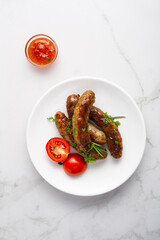 Top view of lamb beef grilled sausages smoked food and tomatoes on plate herbs and sauce