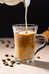 Pouring milk in dark coffee drink concept