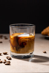 A glass of dark coffee drink with milk or cream concept beans on table black