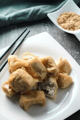 Fried tofu served in a white plate with tamarind sauce and mashed beans, fried tofu is a popular dish among Chinese and Asians.
