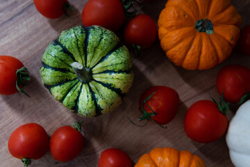 colorful pumpkins with tomatoes on a wooden table with a blurred background. autumn harvest atmosphere.