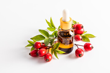 cosmetic bottle with a pipette with organic rosehip seed oil among ripe fruits on a white background. natural cosmetics for skin care. A blank layout.