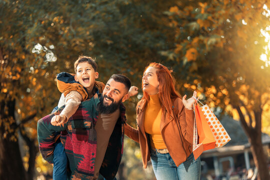 Young happy parents having fun with their boy while in the park during autumn day.
