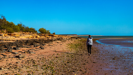 girl walks on red sand beach with red cliffs in the background, terra rosa in australia, holidays in western australia, francois peron national park