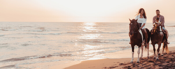 The family spends time with their children while riding horses together on a sandy beach. Selective...