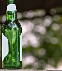 Zielona , pusta , butelka po piwie . Opróżniona przez konsumenta który , po spożyciu napoju , odstawił puste naczynie na murek przed domem . - obrazy, fototapety, plakaty