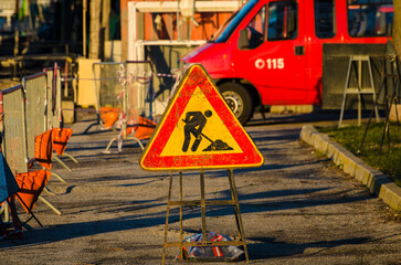 Il cartello di lavori in corso illuminato dalla luce del tramonto