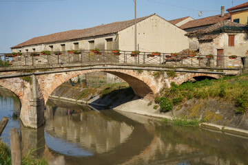 Fototapeta na wymiar Old buildings along a canal near Badia Polesine