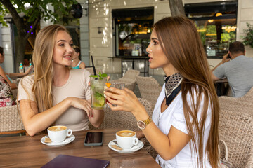 Two girlfriends talking in a outside cafe bar