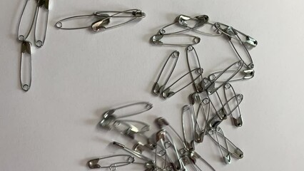 Moving safety pins on a white surface. Random movements introduced by a hidden magnet - old children's party trick