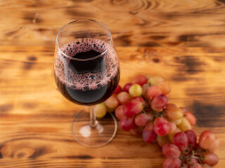 Glass of wine and grapes on a wooden background.