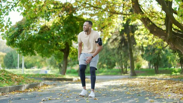 young runner athlete with muscle pain. Man massaging Stretching, trauma injury while jogging in a park or square outdoors. Fitness male sprain severe pain stretch pull. Leg muscle cramp calf sport