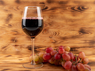 Glass of wine and grapes on a wooden background.