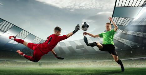Scoring moment. Football goalkeeper in gates jumping to catching flying ball during soccer match at...