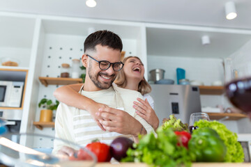 happy young couple have fun in modern kitchen indoor while preparing fresh fruits and vegetables...