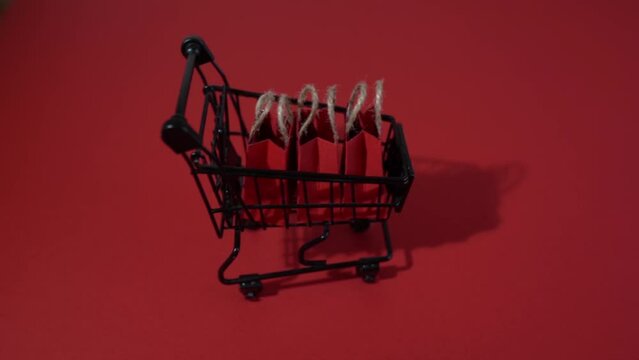 Shopping cart with paper bags on red background. Black friday, shopping and celebration concept