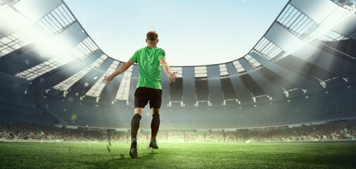 Winner emotions. Back view of soccer player running at the crowded stadium with spot lights during evening football match. Concept of sport, competition, championship