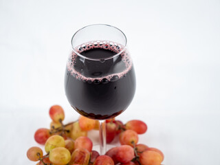 A glass of wine and grapes on a white background.
