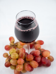 A glass of wine and grapes on a white background.