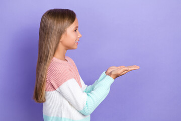 Profile side photo of cute positive girl arm demonstrate look empty space dressed stylish sweater isolated on purple color background