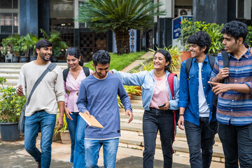Fototapeta premium focus on girl, Group of students talking each other after class at college campus - concept of friendship, enjoyment and millennial lifestyle.